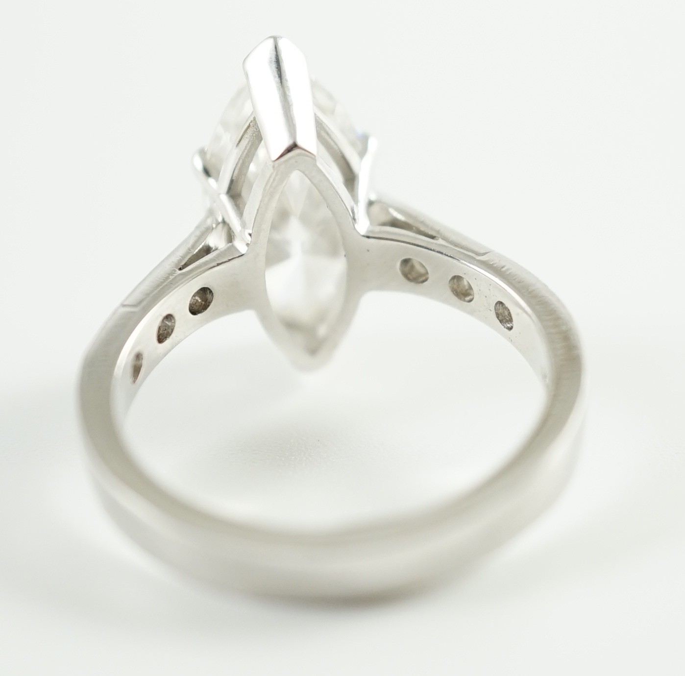 A modern 18ct white gold and single stone marquise diamond set dress ring, with graduated diamond set shoulders, with accompanying WGI report dated 18/6/2021, stating the stone to weigh 3.70ct